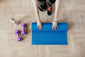 Yoga mat and water bottle on a wooden floor.